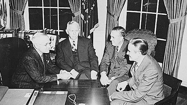 black and white photo of the four men seated by the desk in the oval office