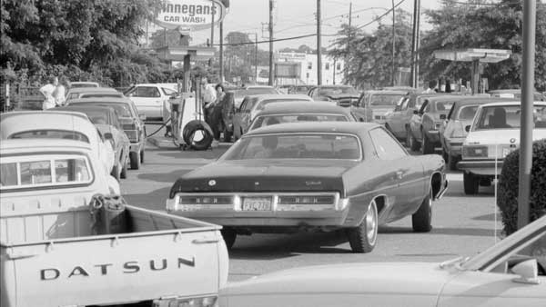 black and white photo of a large number of cars waiting in line for gas