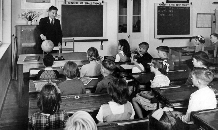 black and white photo of teacher in front of students at desks
