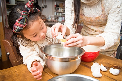 a young girl helping her mother make cake batter