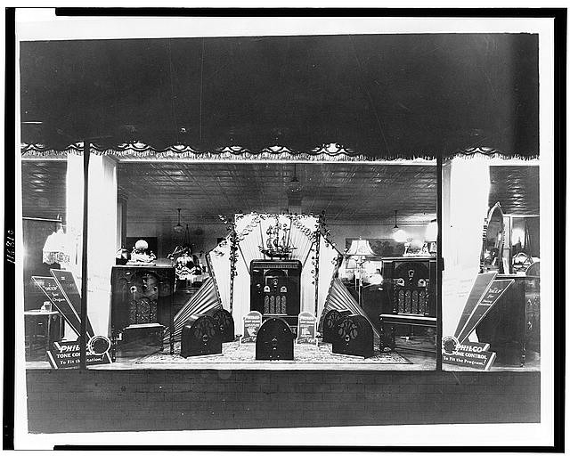 black and white photograph of radios displayed in a store-front window