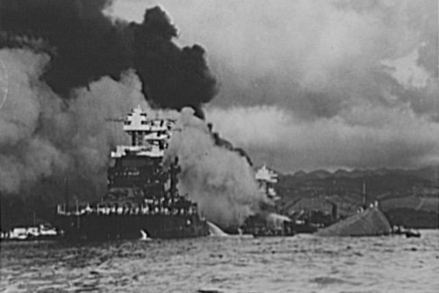 black and white photo of a ship sinking in Pearl Harbor