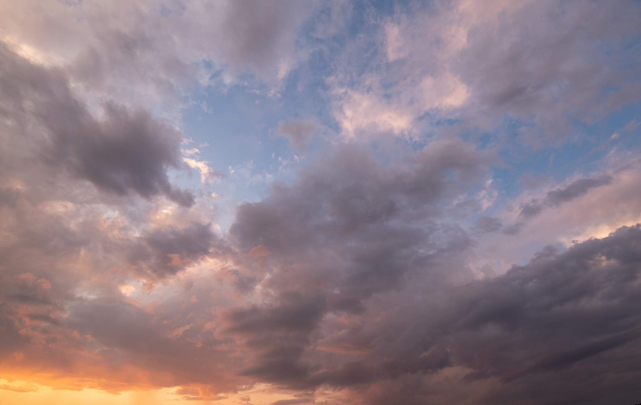 A cluster of clouds form above the horizon of the ocean.
