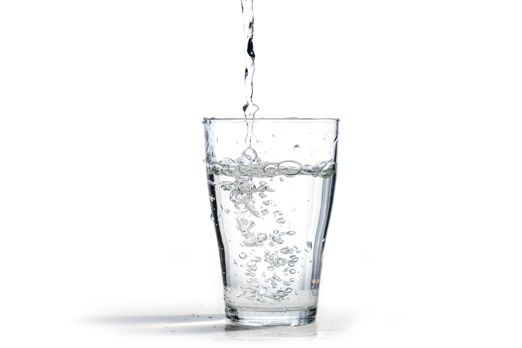 Water is poured into a glass. There are bubbles in the glass.