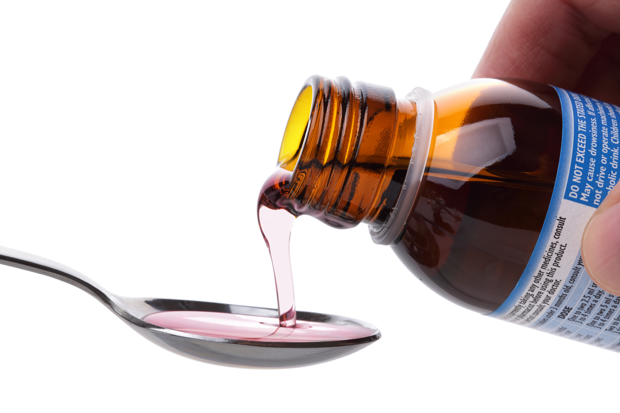 Cough syrup is poured on a spoon.